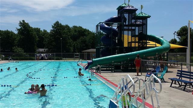 Children are playing in a large pool with a slide